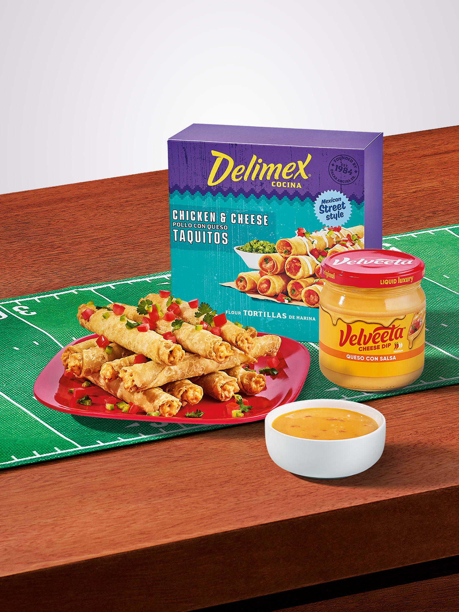 Delimex taquitos with Velveeta queso dip on a game day field.
