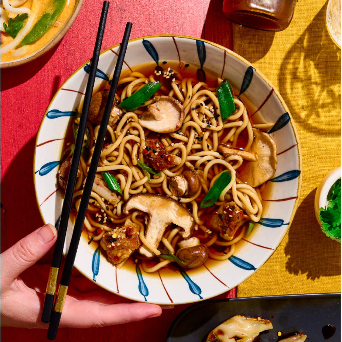 Bowl of noodle soup with mushrooms and chopsticks.