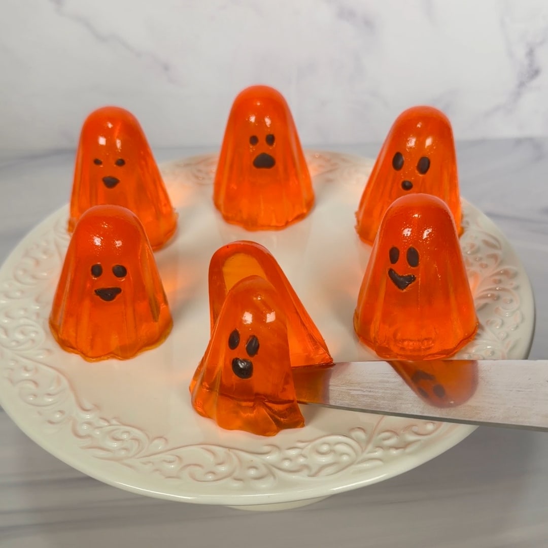 Orange JELL-O ghost jigglers being served from a plate