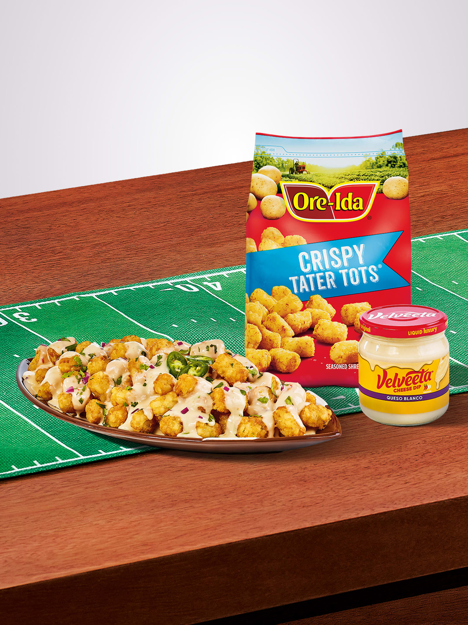 Ore-Ida crispy tater tot nachos (Totchos) with Velveeta Queso Blanco on a game day field.