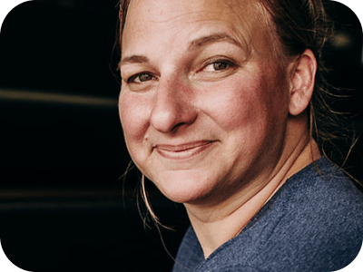 A woman smiles next to a bread rack.