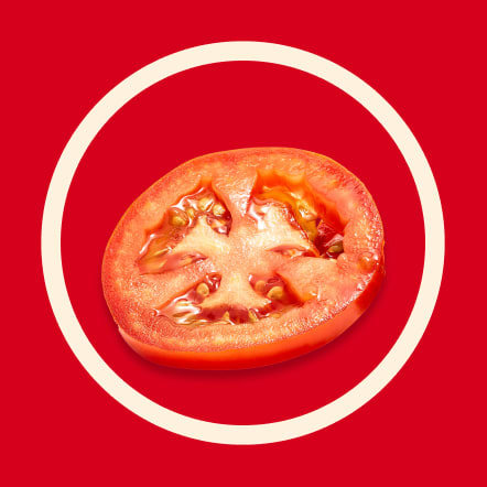 A single, thin slice of a ripe red tomato is centered on a vibrant red background within a contrasting off-white circle. This image visually represents a single serving size for a recipe.