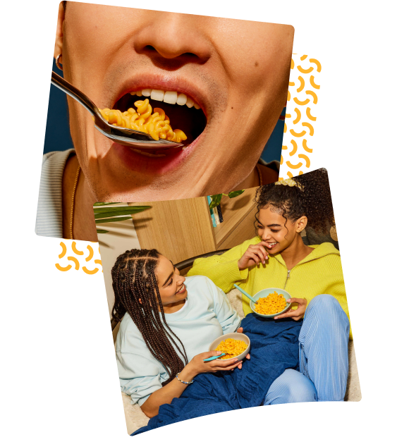 Close-up of a person's mouth eating a spoonful of Kraft Mac & Cheese. Two close friends sit together laughing and catching up with each other over their yummy bowls of Kraft Mac & Cheese.