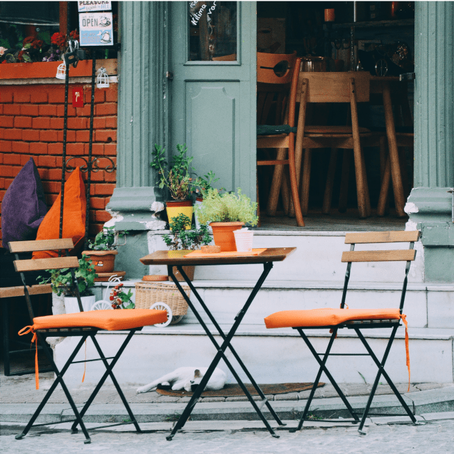 A number of 3-piece patio sets outside of a coffee shop