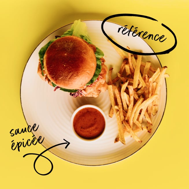Burger, fries and spicy sauce on a plate in front of yellow background