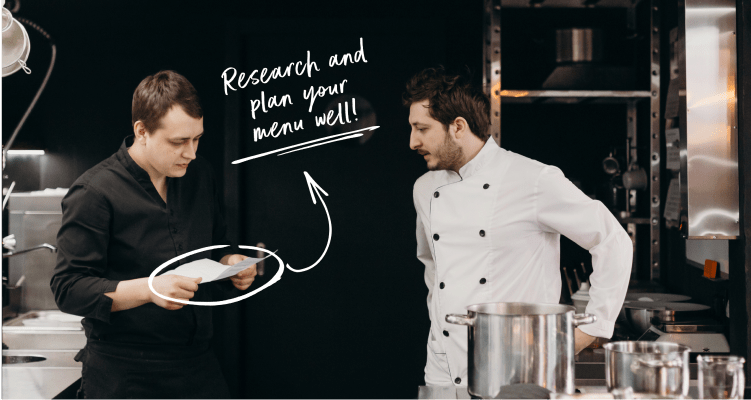 Chefs discuss menu in a kitchen.
