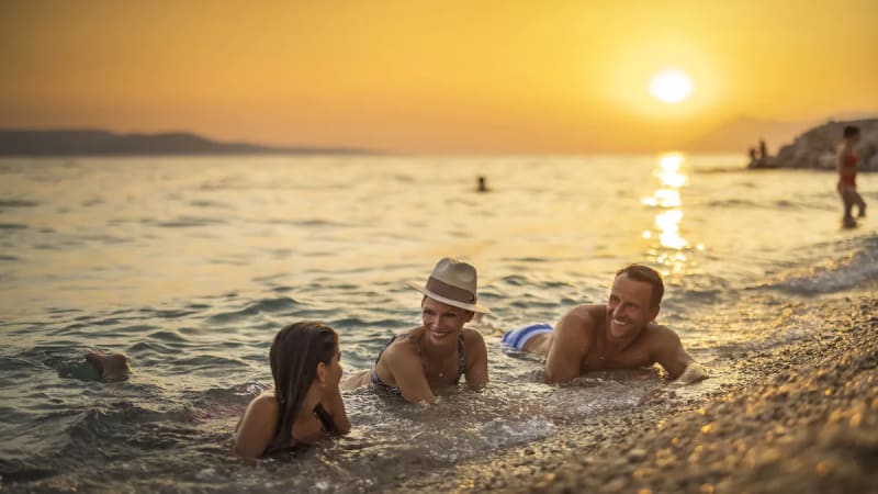 Tre personer badar i solnedgngen i Kroatien