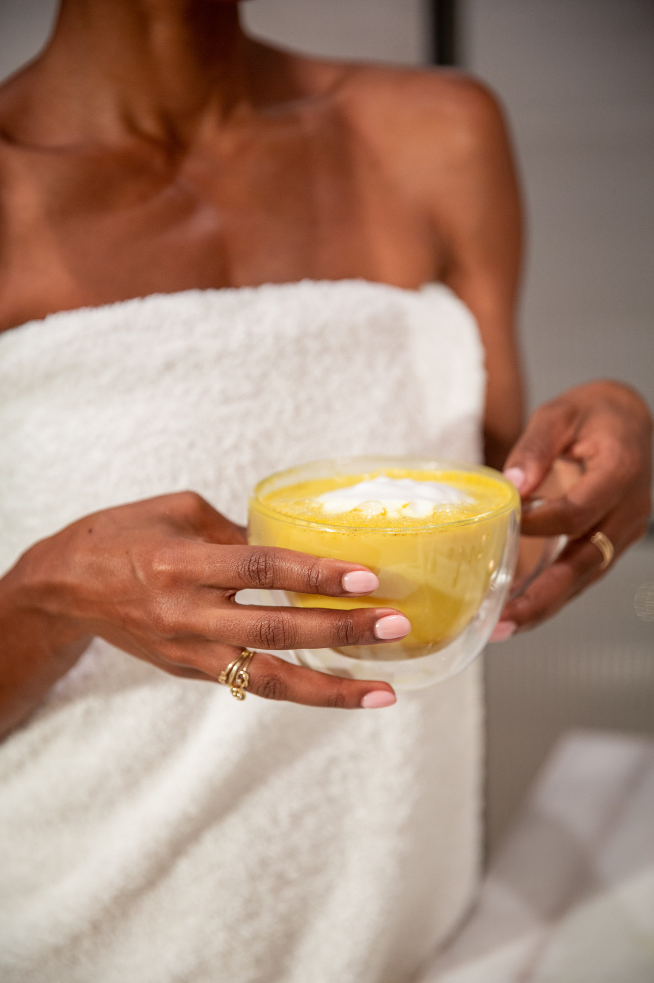A woman in a towel holding a mug of Kroma Ultimate Vitality Latte.