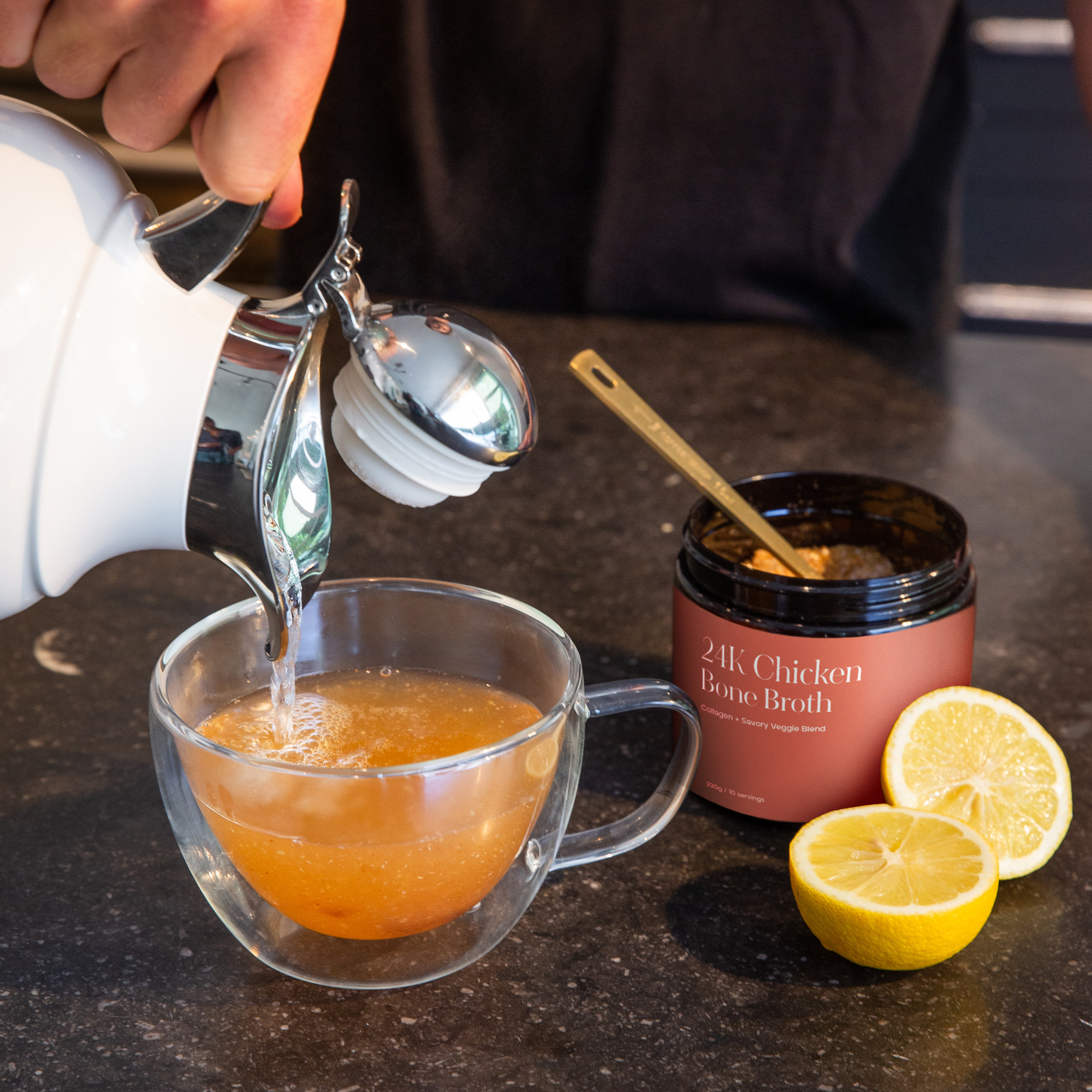 A person preparing a mug of Kroma 24K Chicken Bone Broth next to the product jar.
