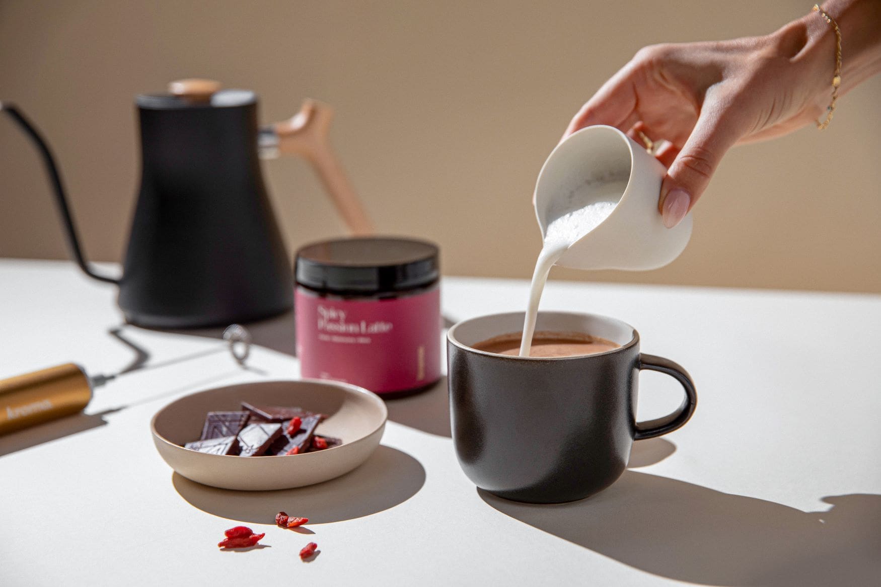 A person preparing a mug of Kroma Spicy Passion Latte.