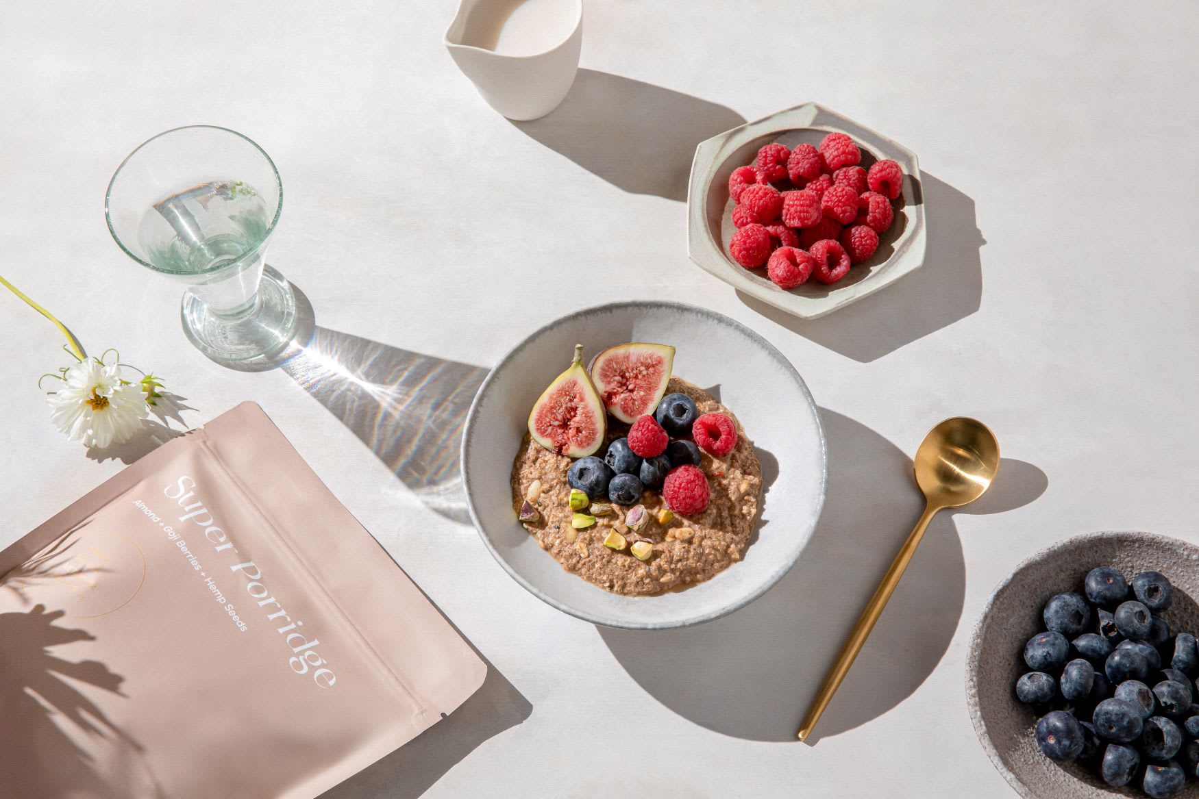 A bowl of prepared Kroma Super Porridge with fruit and a gold spoon.