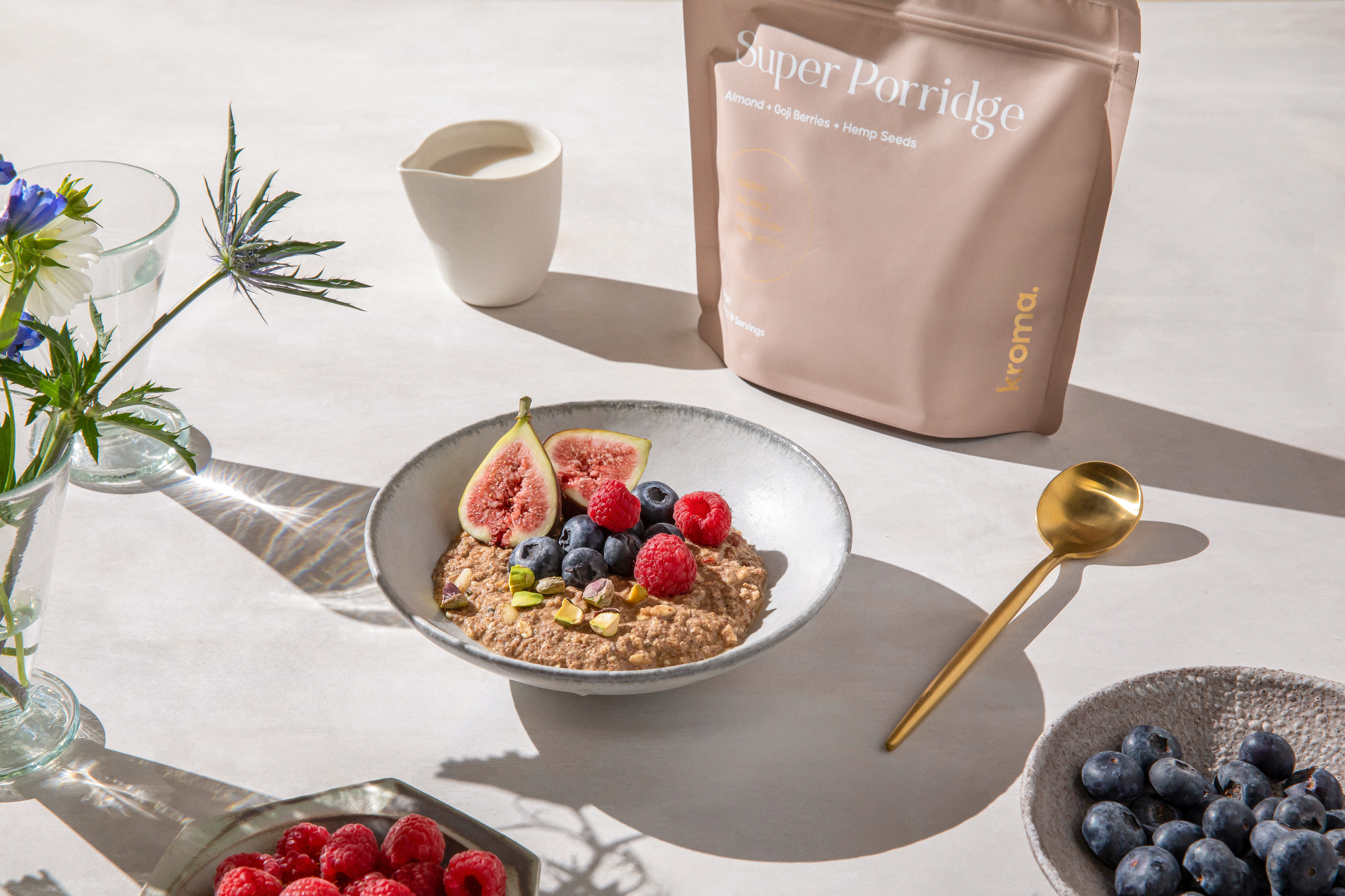 A bowl of prepared Kroma Super Porridge next to a Kroma golden spoon.
