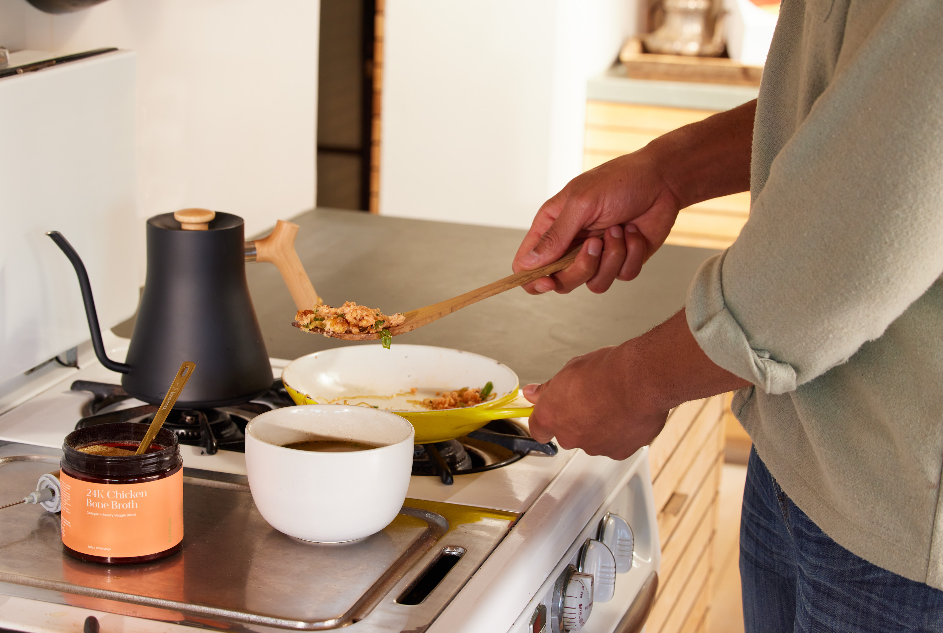 A man preparing a bowl of soup using Kroma 24K Chicken Bone Broth.