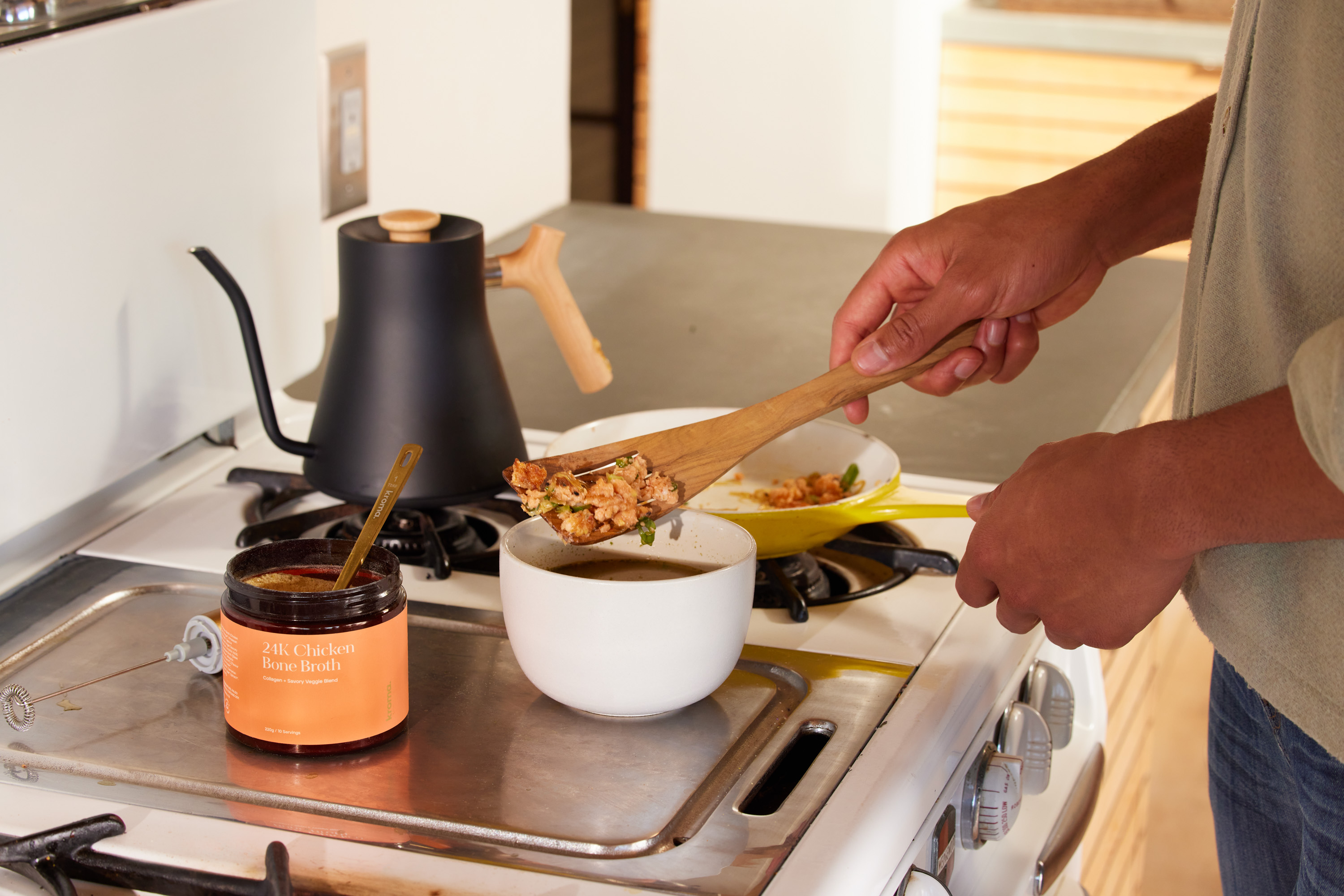A man preparing a bowl of soup using Kroma 24K Chicken Bone Broth.