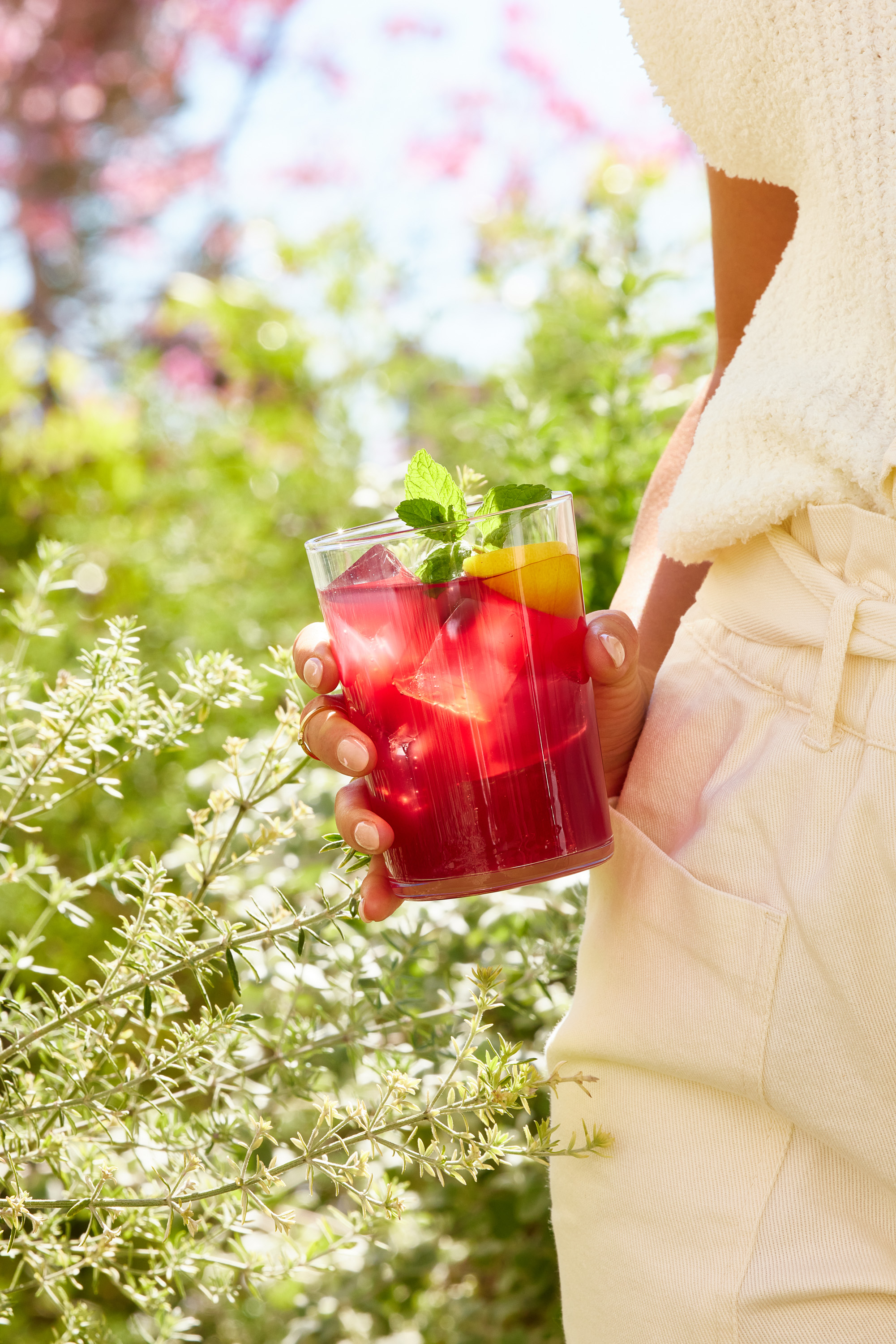 A woman holding a glass of Kroma Cranberry Hydration Elixir mocktail.