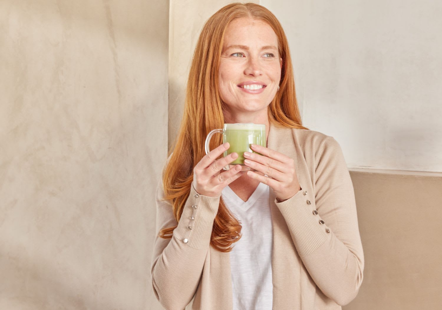 A woman holding a mug of Kroma Beauty Matcha Latte.