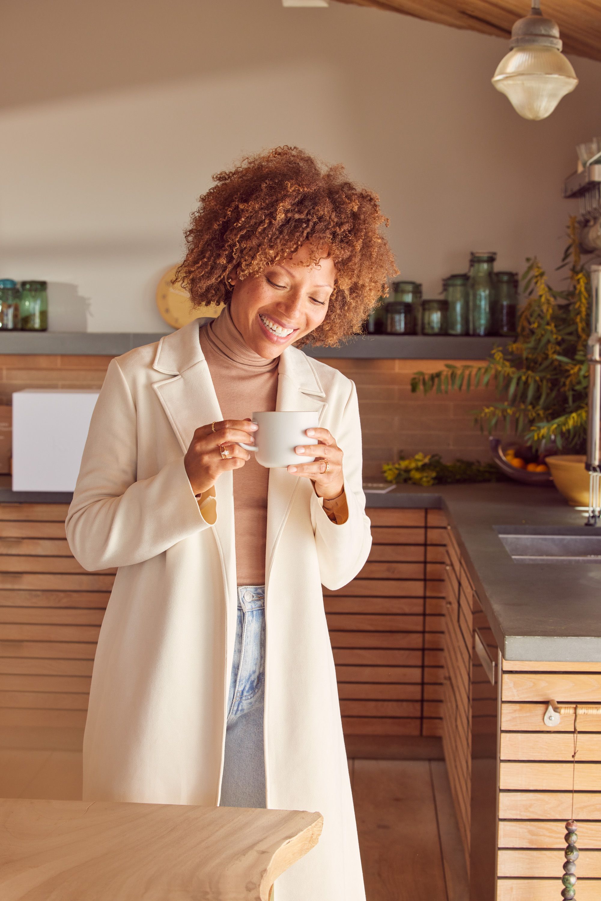 A woman smiling and holding a mug.