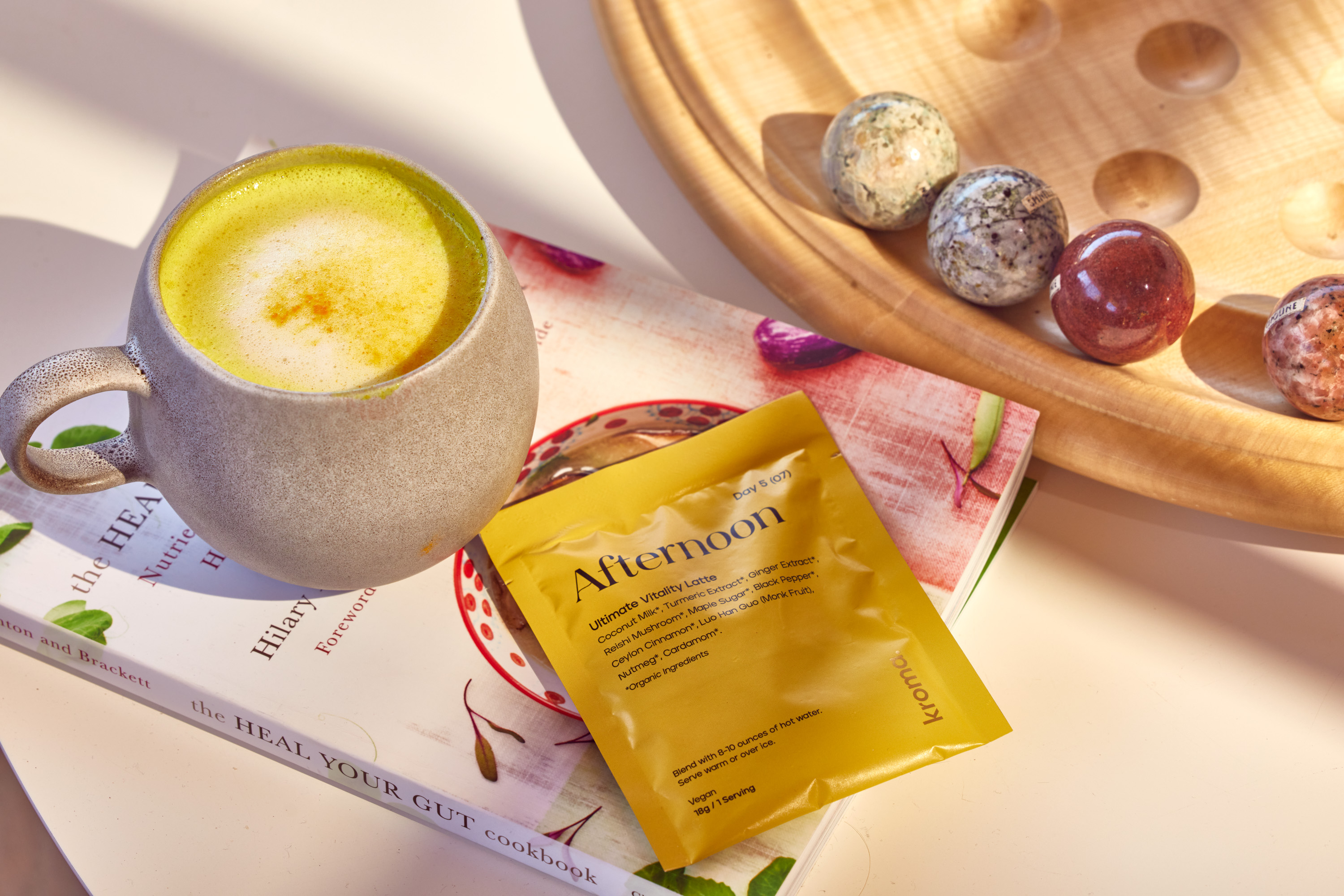 A mug of Kroma Ultimate Vitality Latte next to a sachet of Kroma Ultimate Vitality Latte.