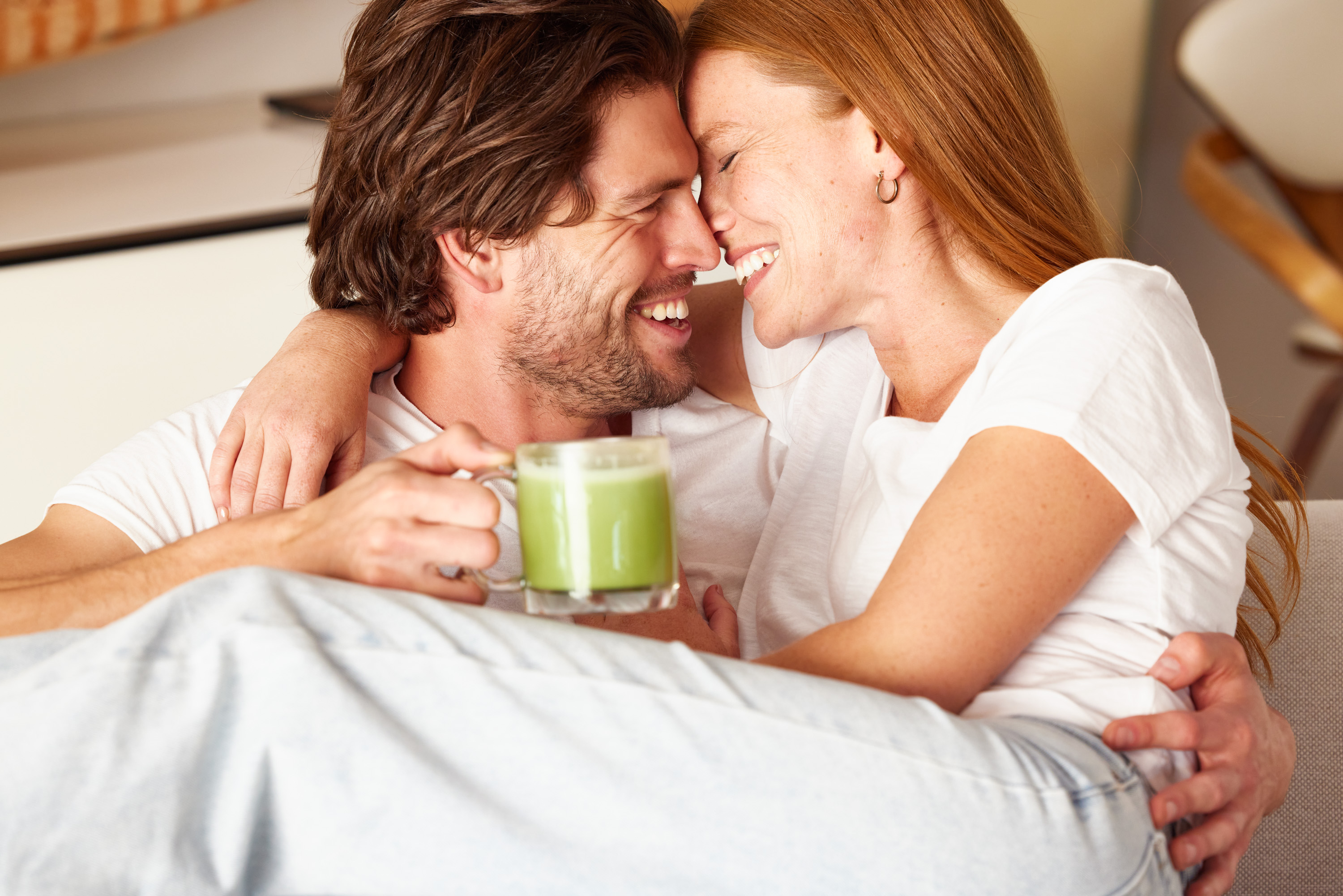 A man embracing a woman while holding a mug of Kroma Beauty Matcha Latte.