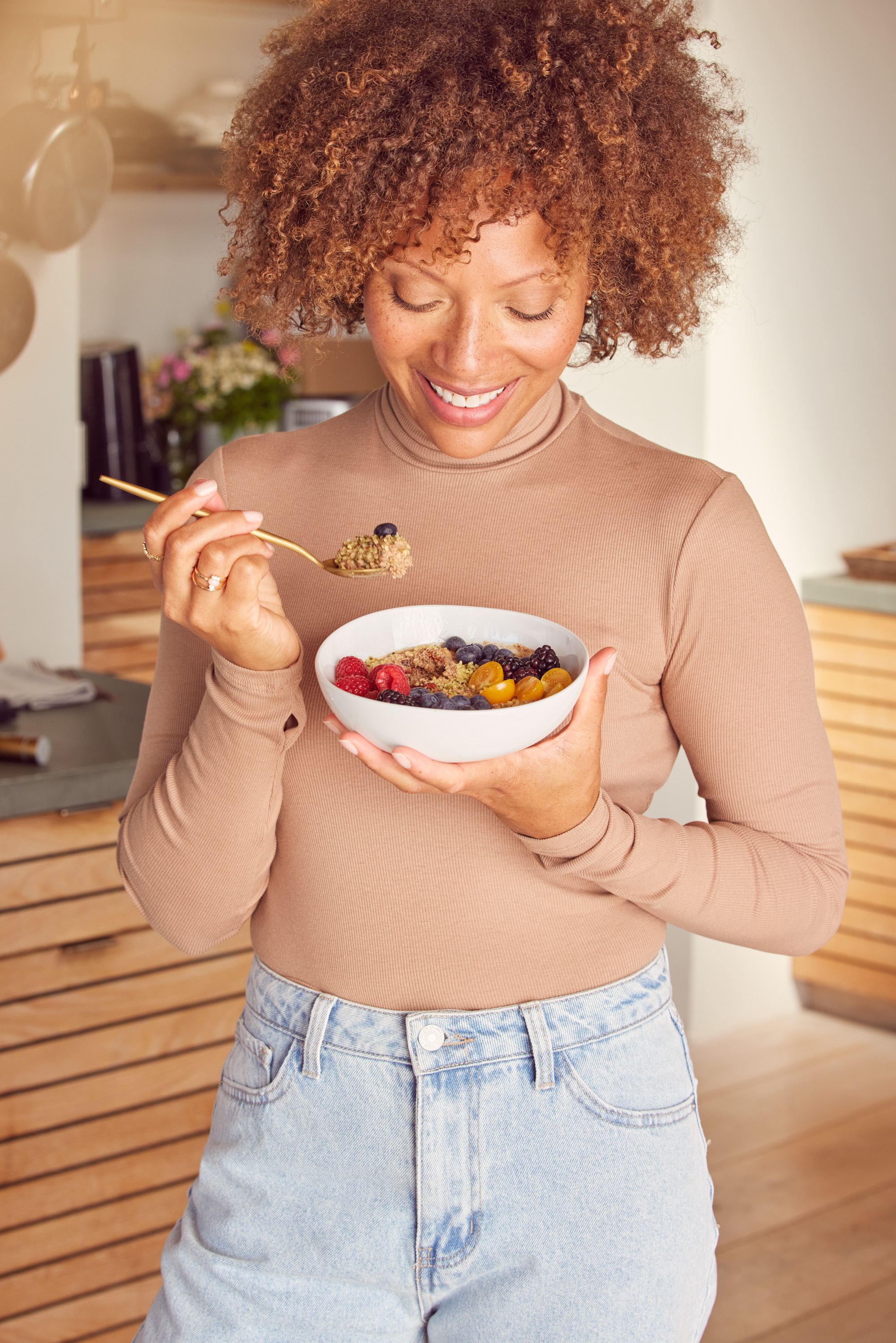 A woman eating a bowl of prepared Kroma Super Porridge with fruit.