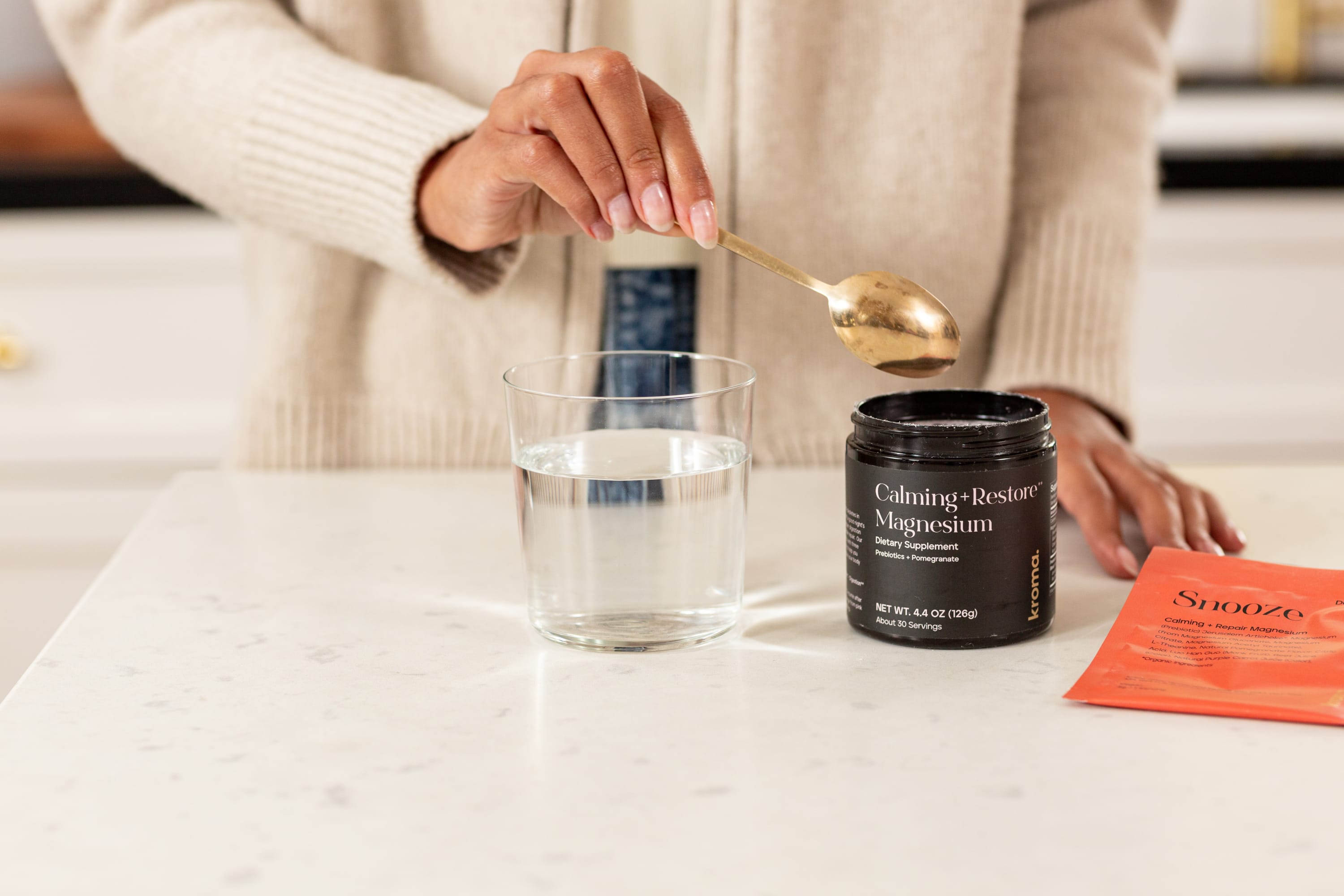 A woman preparing a glass of Kroma Calming + Restore Magnesium.