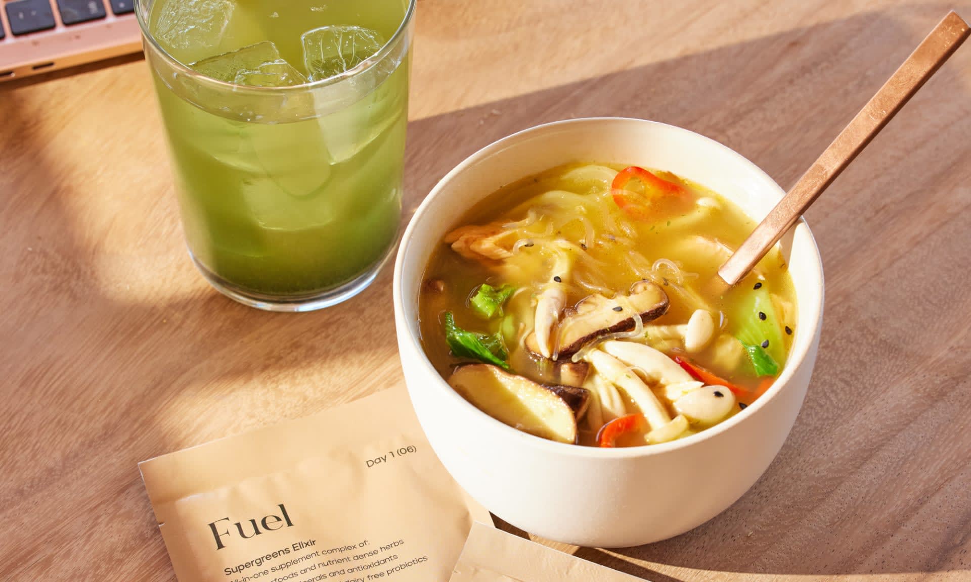 A warming bowl of  Kroma 24K Chicken Bone Broth and a glass of Kroma Supergreens Elixir.