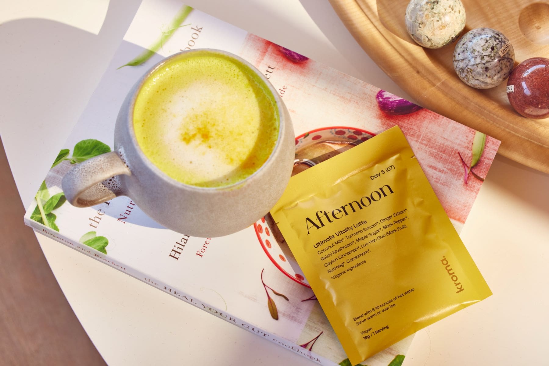 A sachet of Kroma Ultimate Vitality Latte beside a mug of Ultimate Vitality Latte.