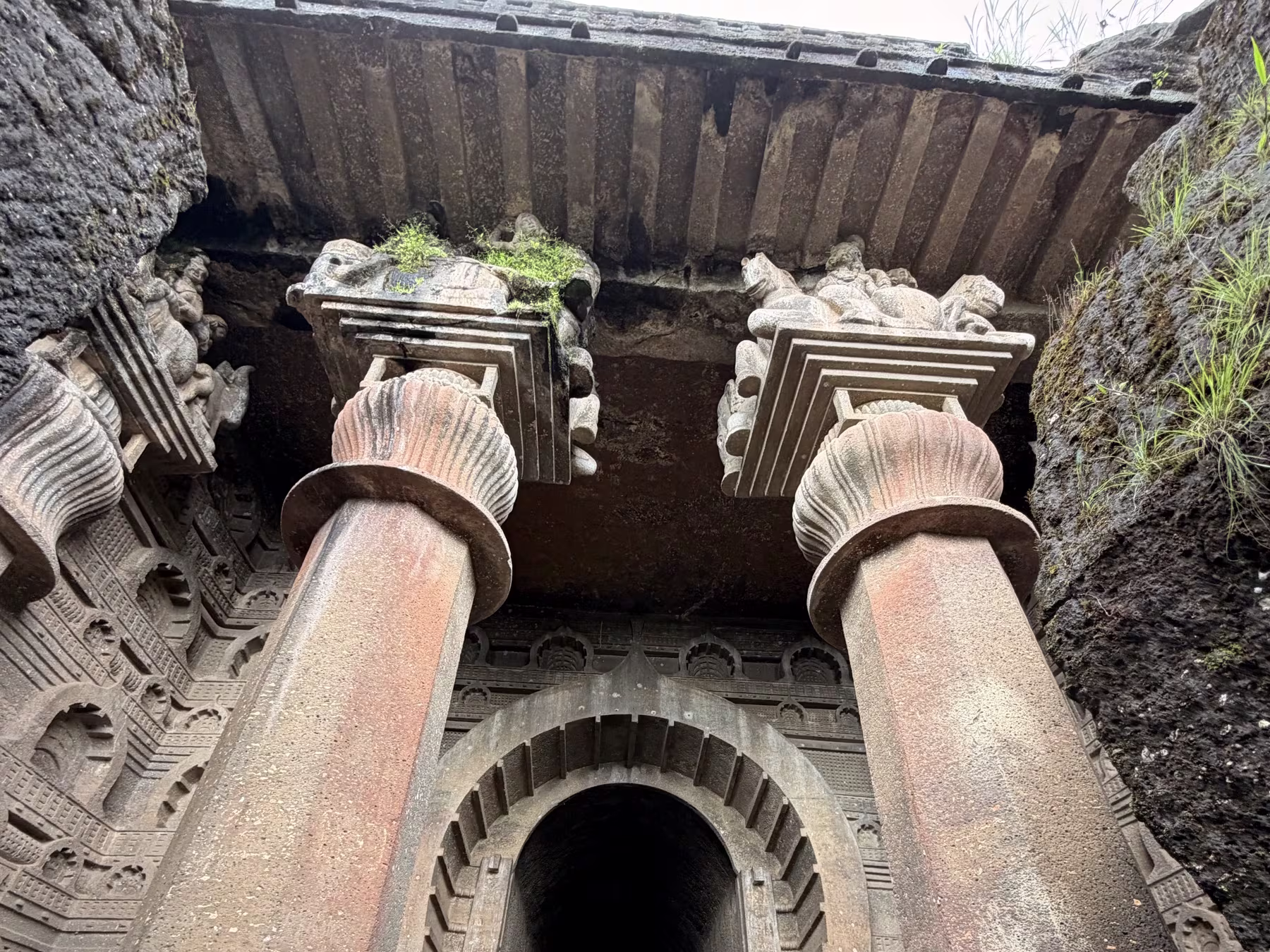 The grand rock-cut entrance and ribbed ceiling of Bedse Caves The monumental Chaitya hall facade and monolithic pillars of 1st-century BCE Bedse Caves