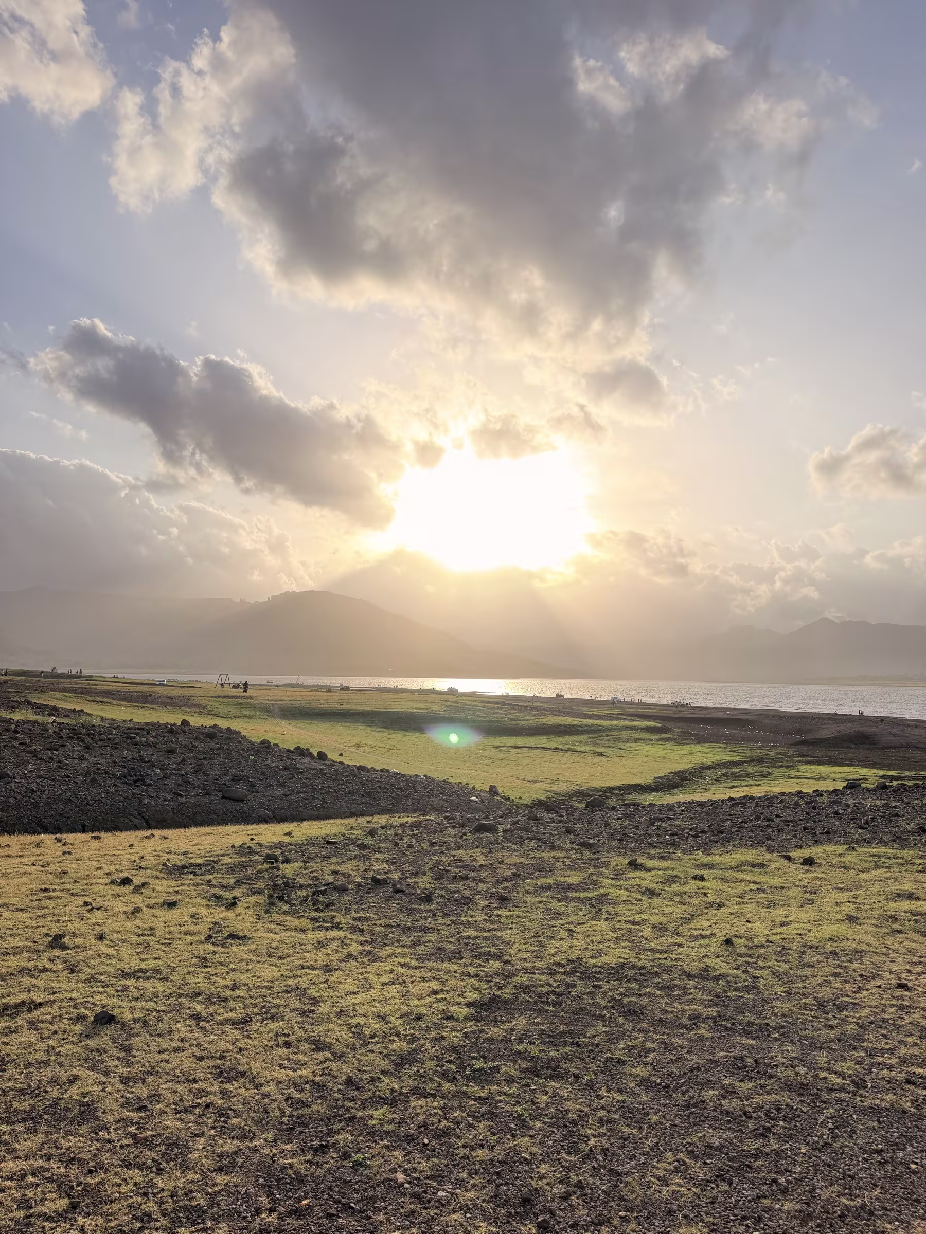 Golden sunburst breaking through dramatic evening clouds over the shores of Dhom Dam