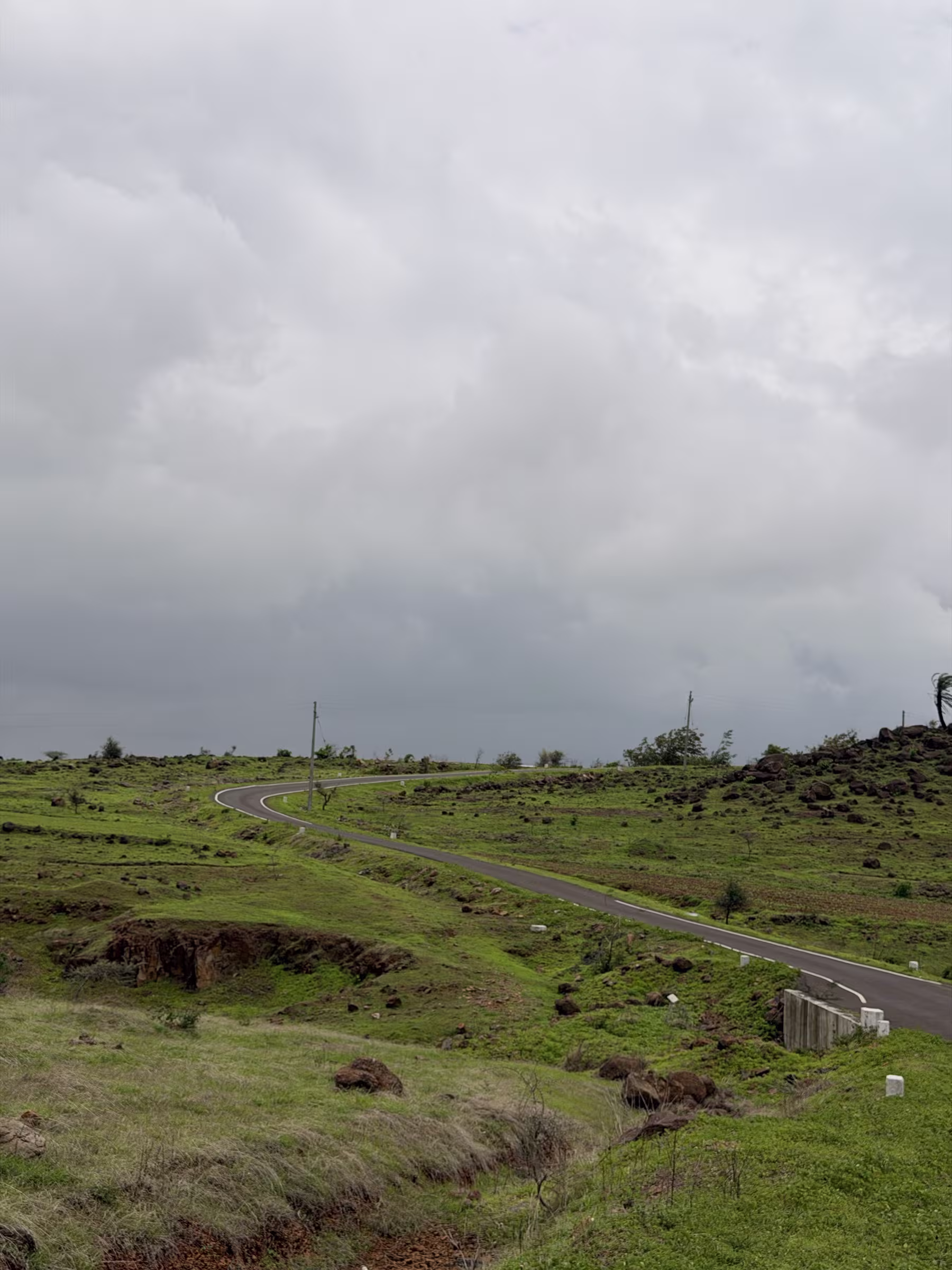 Scenic rolling curves on the approach road toward Malshej Ghat under dramatic monsoon clouds