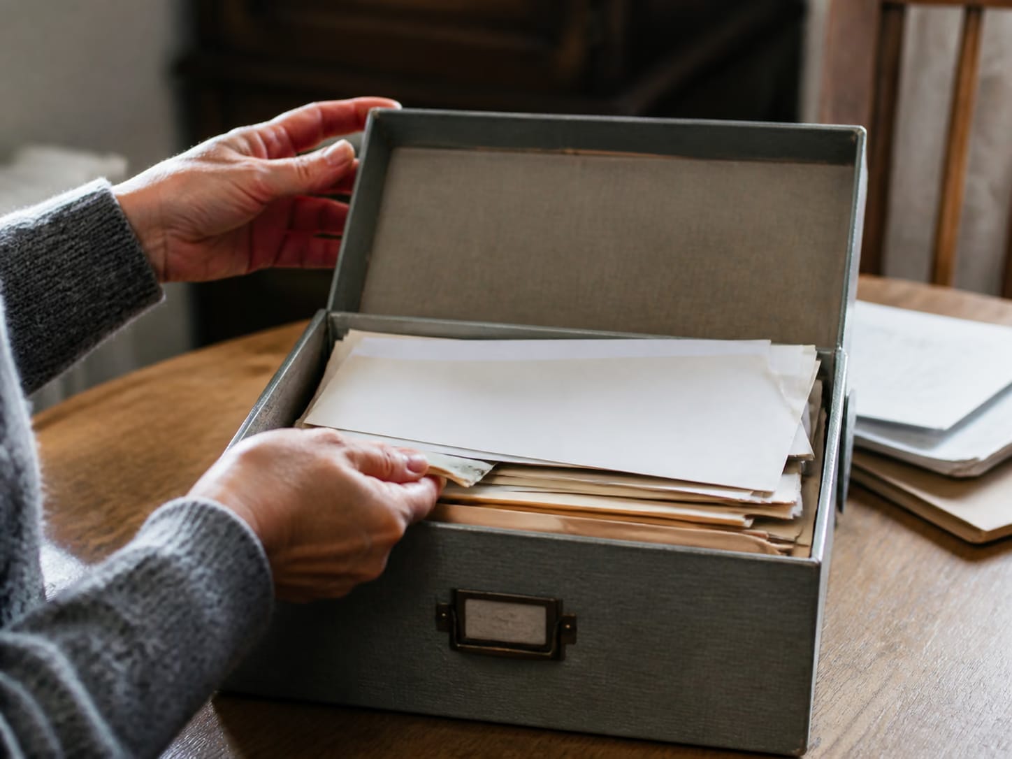 A filing box of older paperwork being opened on a table.