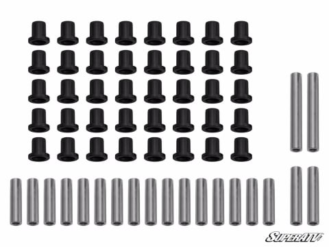 Full A-arm bushing kit laid out: 40 black flanged bushings in rows and 20 steel sleeves in two lengths.
