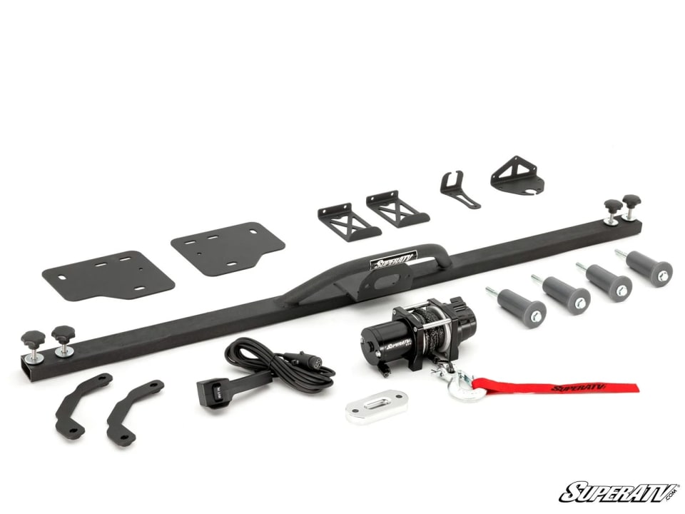 Bed winch kit laid out: black steel crossbar with a winch hoop, winch with red hook strap, corded remote, mounting plates, brackets, knobs and gray spacers.