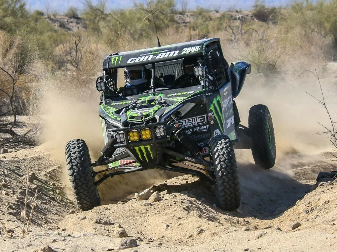 Race UTV crossing rough desert terrain with dust behind it