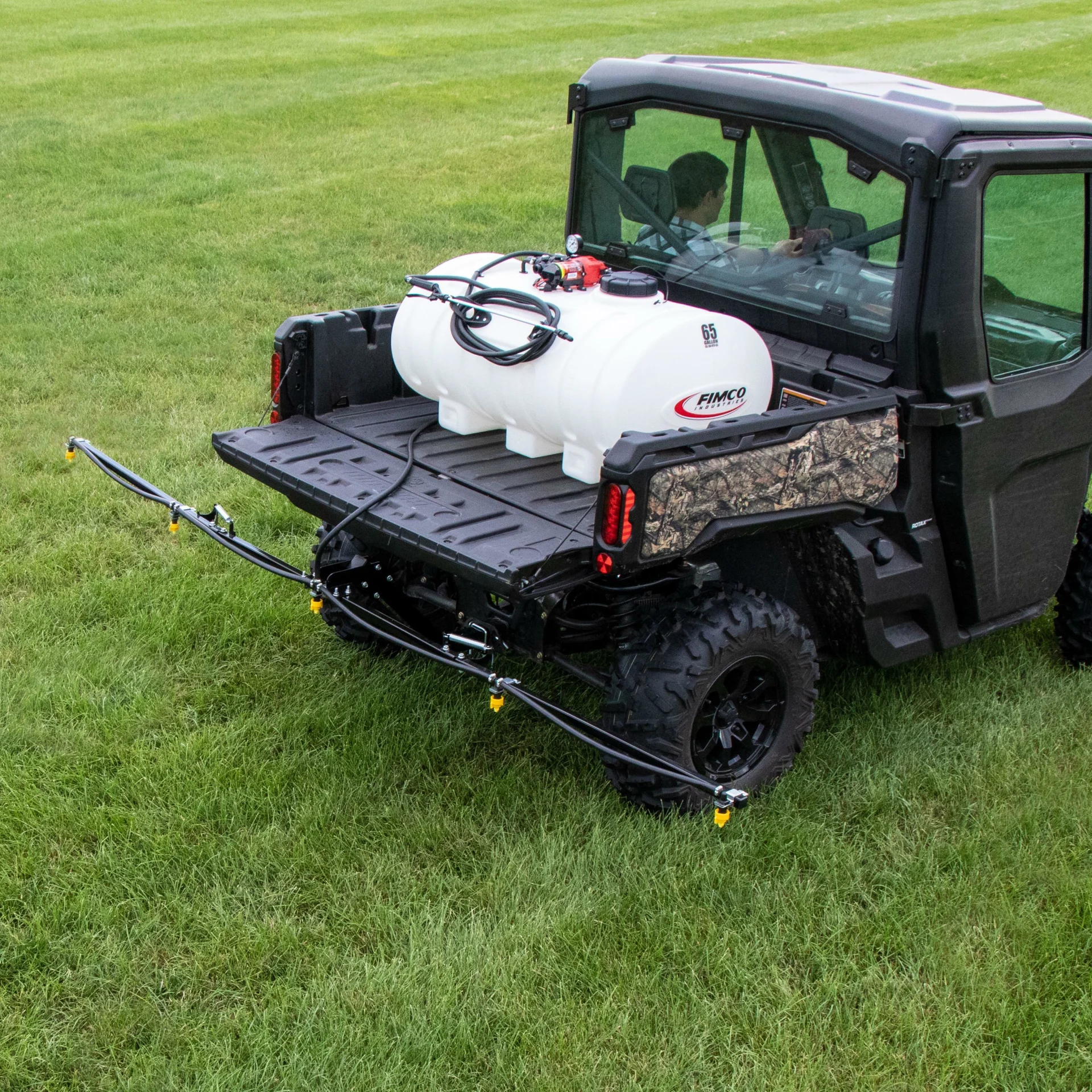 FIMCO 65-gallon Value Series sprayer mounted in a UTV cargo bed, rear angled view with boom extended