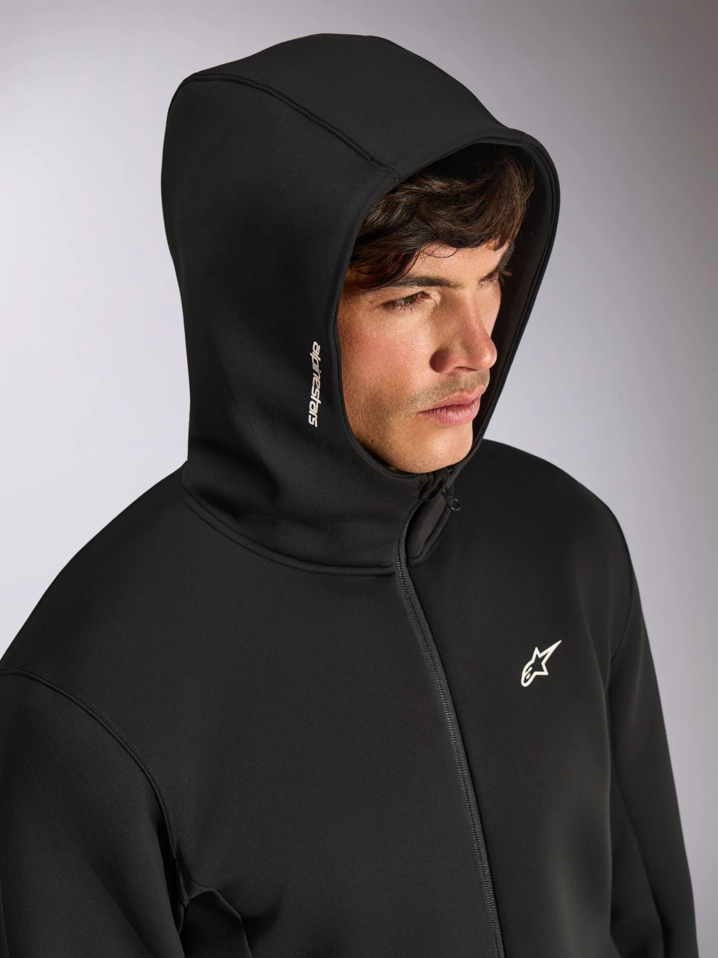 Model wearing the black Alpinestars Cypher zip hoodie with the high-neck hood up