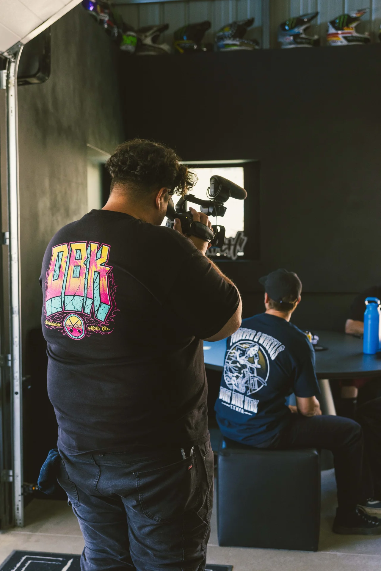 Person wearing the DBK Block X Block Tee in black, back view, in a shop setting