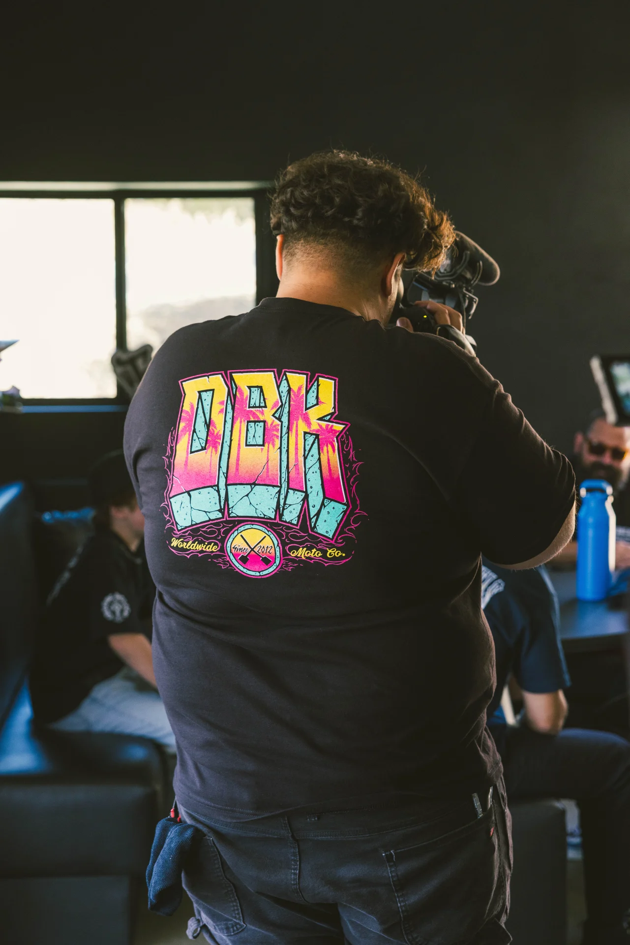 Person wearing the DBK Block X Block Tee in black, close back view of the DBK graphic