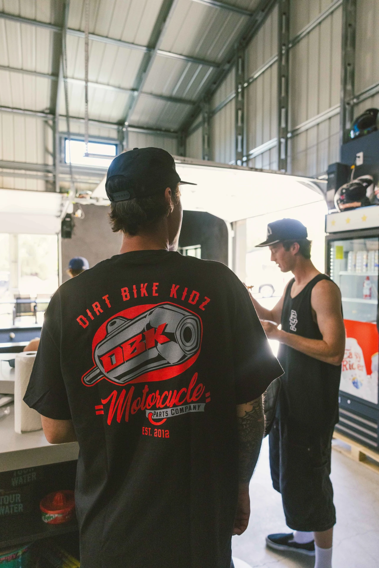Person wearing the black DBK Factory tee in a garage, back view