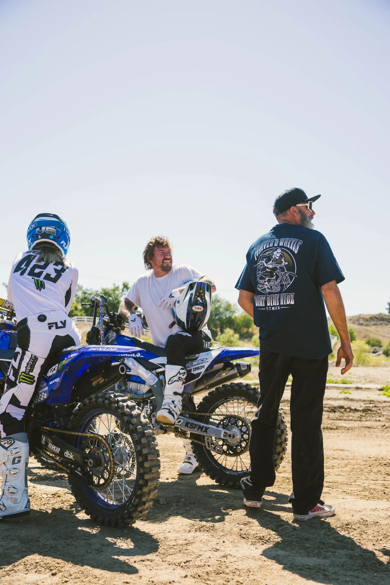 DBK Ghost Rider Tee in navy worn at a dirt track, back view beside riders on dirt bikes