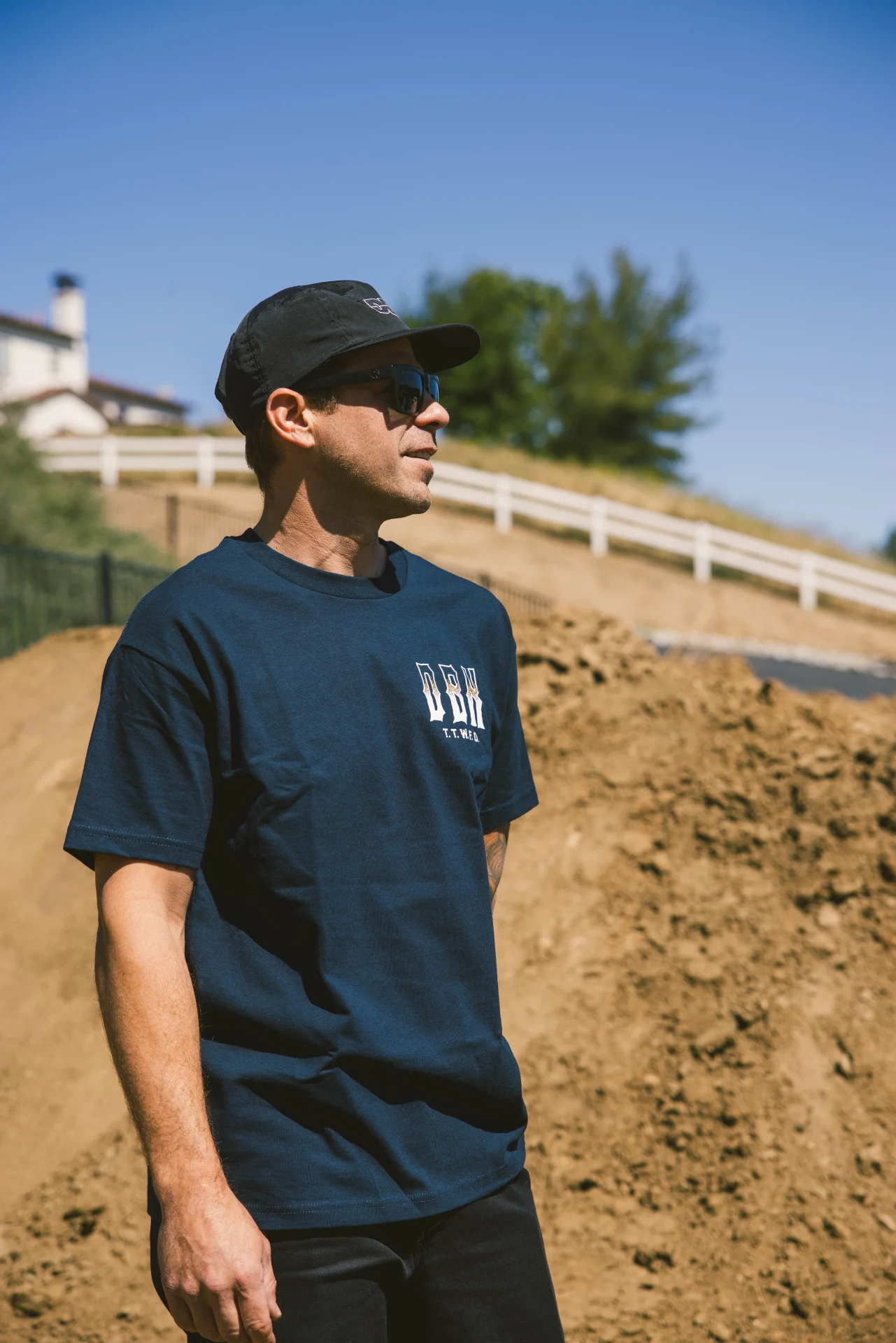 Man wearing the DBK Ghost Rider Tee in navy, standing outdoors by a dirt hill