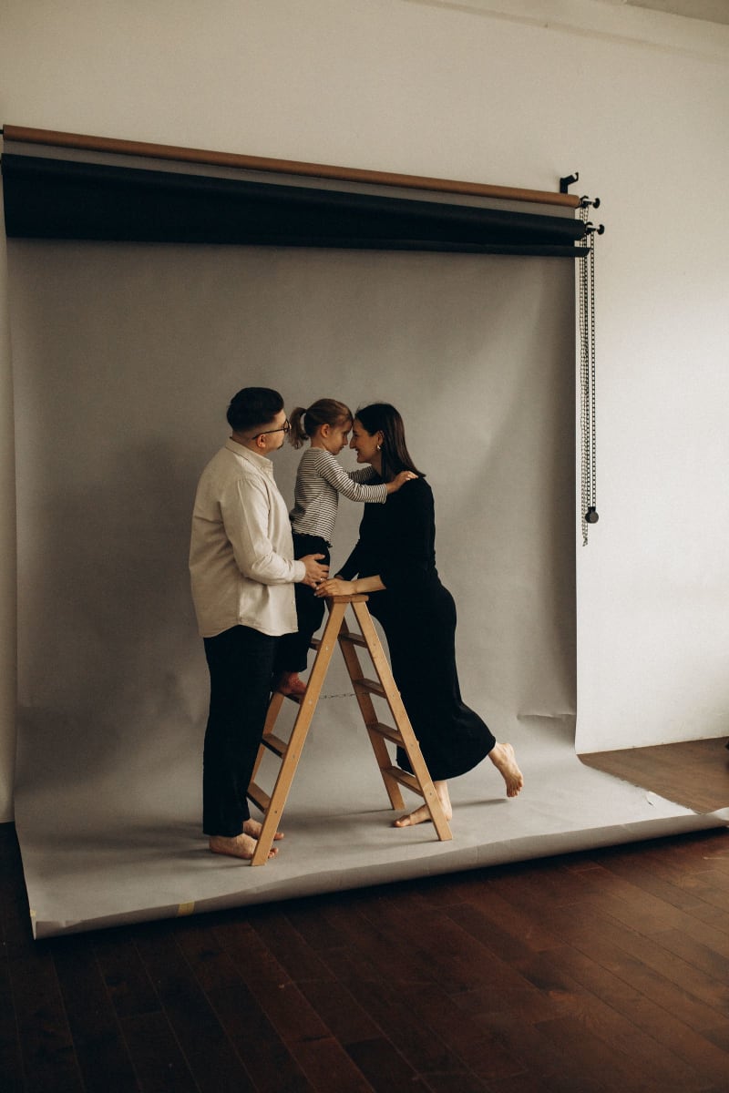 Sesión de fotos familiar en estudio: papá, mamá y su hija frente a un fondo gris