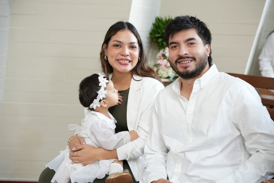 Fotografía de bautizo en Lima: papá y mamá con Zoe en brazos dentro de la iglesia