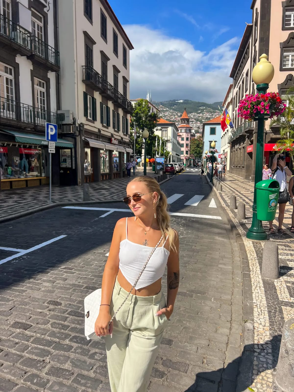 Girl on a street in the center of Funchal on Madeira Island with a cathedral and mountains in the background