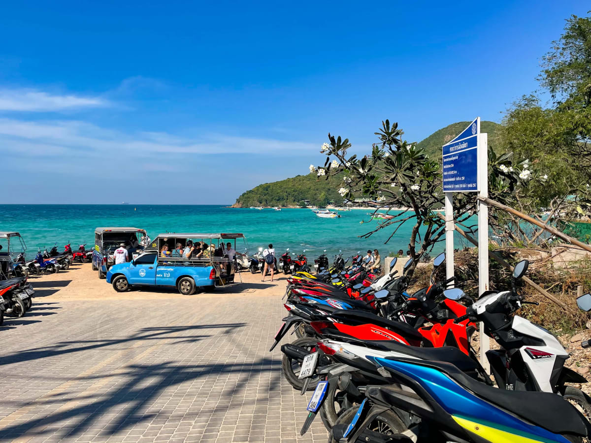 Motorbikes and songthaews parked in front of Tien Beach on Koh Larn island in Pattaya, Thailand