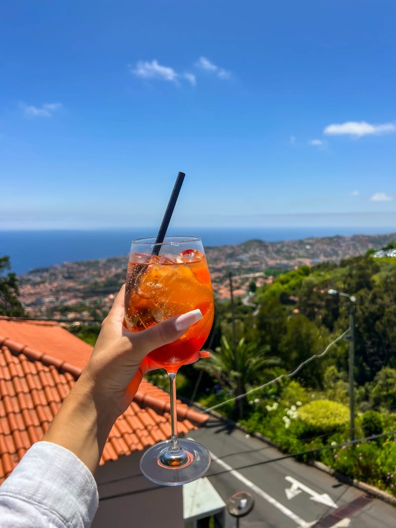 An aperol spritz with distant Funchal city and ocean views on Madeira Island