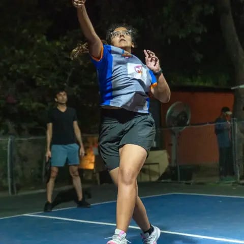 A woman jumping for an overhead smash at a FindYourFit pickleball tournament