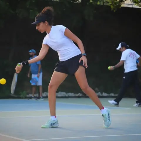 A woman lunging for a forehand return at a FindYourFit pickleball night