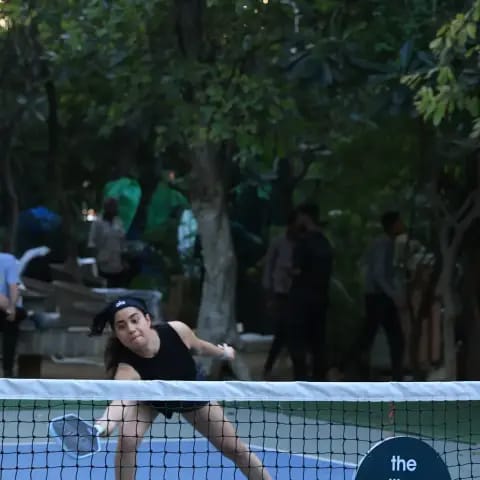 A woman reaching for a net shot at a FindYourFit pickleball night