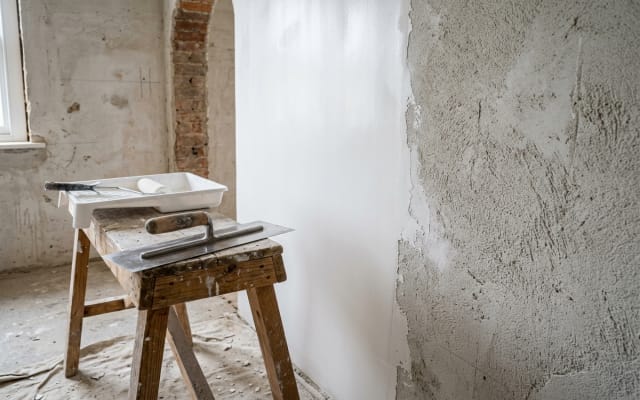 Substrate surface preparation and plaster skim coating with trowel on masonry wall